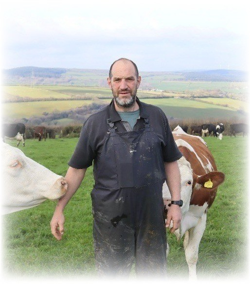Farmer jj-wilcocks stands in a field with his cows.